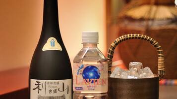 Una botella de sake, una botella de agua y un cubo de metal con hielo sobre una bandeja.