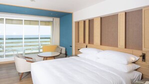 A hotel room with a large bed, a small round table, a sofa, and a view of the ocean. - Rizzan Sea Park Hotel Tancha Bay (Onna)