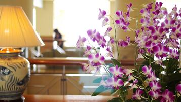 A table with a lamp and a vase of purple orchids.
