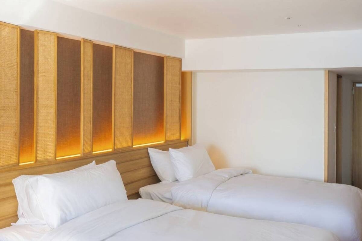 A hotel room with two beds, a wooden headboard, and a wall with vertical panels.