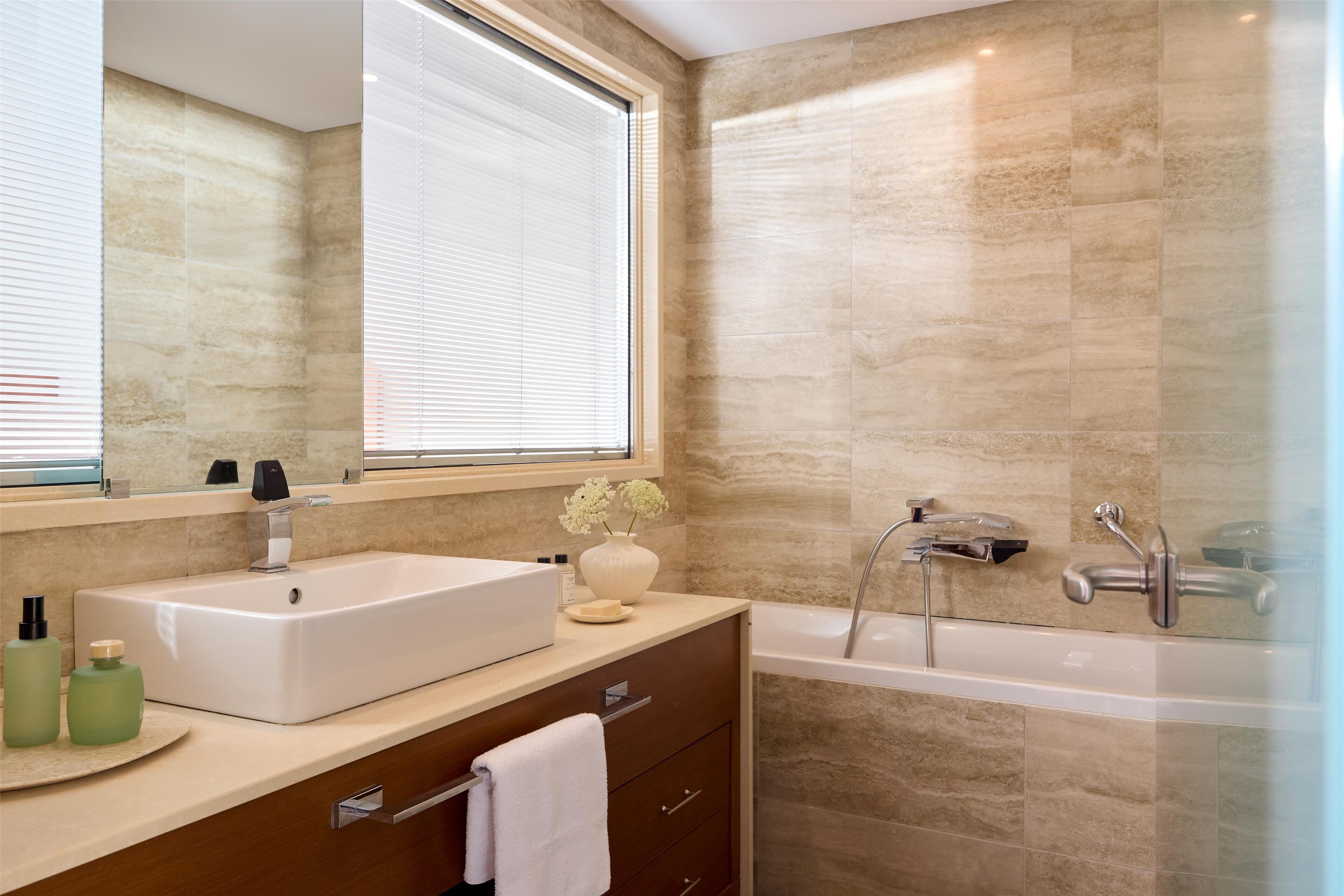 Une salle de bain moderne avec un grand miroir, un lavabo rectangulaire, une baignoire et un meuble-lavabo doté d’un porte-serviettes.