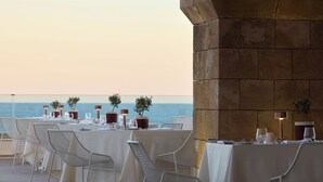 Een restaurant aan zee, met gedekte tafels met uitzicht op de oceaan.
