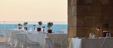 Un restaurante frente al mar, con mesas dispuestas para comer y vistas al océano.