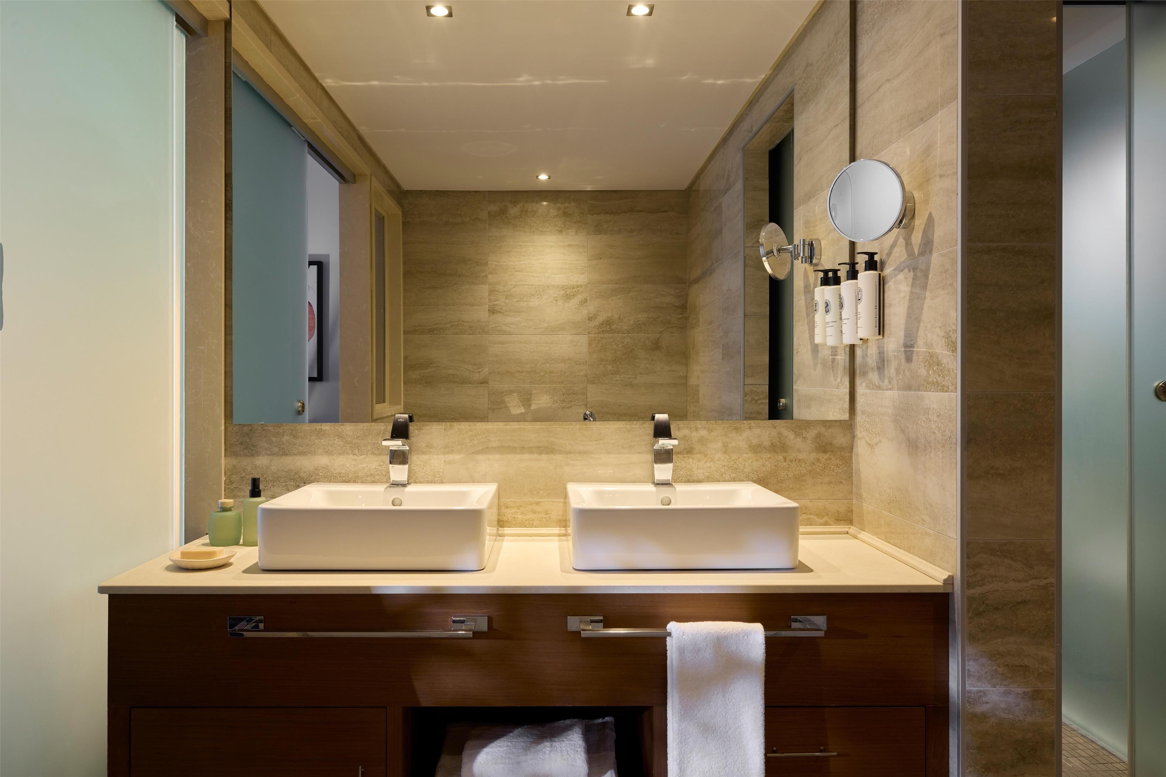 Ein modernes Badezimmer mit zwei Waschbecken, einem großen Spiegel und einem Handtuchhalter.