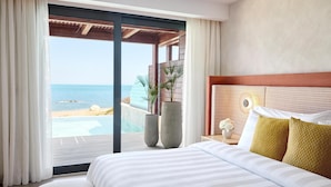 Een hotelkamer met een groot bed, uitzicht op het strand en de oceaan, en een houten plafond.