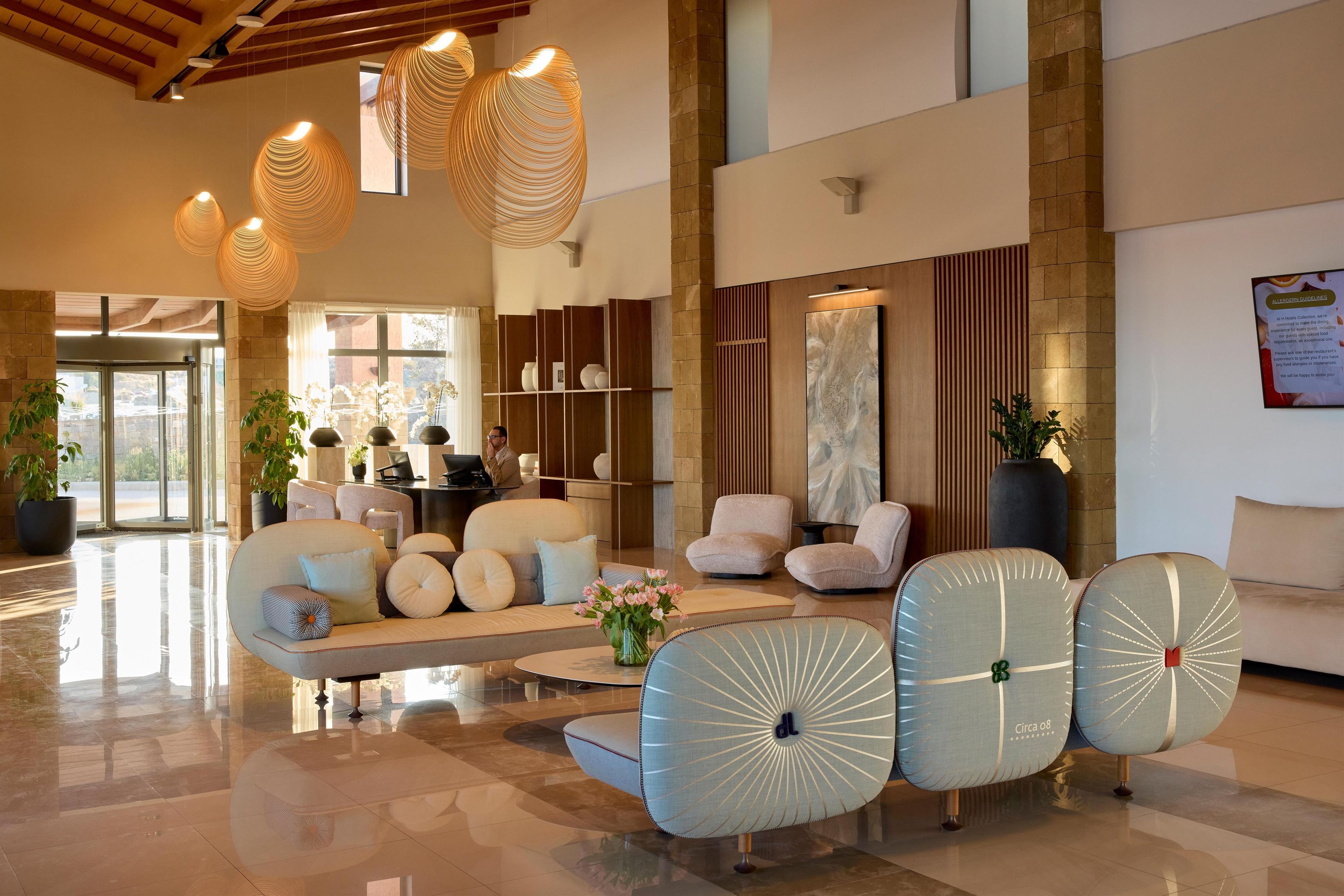 A spacious lobby with modern furniture, a reception desk, and decorative lighting.