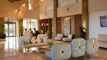 A spacious lobby with modern furniture, a reception desk, and decorative lighting.
