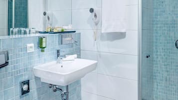 Een moderne badkamer met een witte wastafel, een douchecabine van glas en een douchewand betegeld met blauwe tegels.