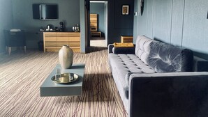 Een moderne woonkamer met een grijze bank, een salontafel en een aan de muur bevestigde televisie.