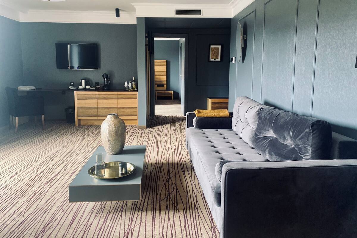 Un salon moderne avec un canapé gris, une table basse et un téléviseur fixé au mur.