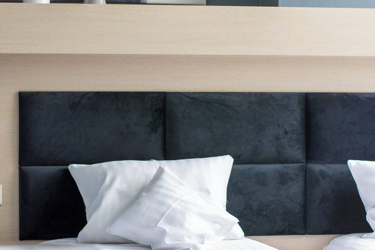 Une chambre d’hôtel moderne avec un grand lit, une tête de lit et un tableau au-dessus du lit.