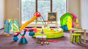 Een speelkamer met een glijbaan, een speelhuus en een schilderij.