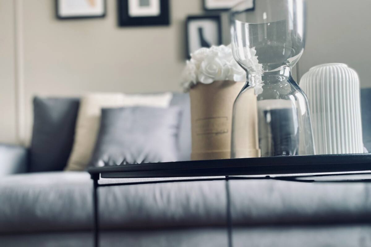 Un salon moderne avec un canapé gris, une table basse agrémentée d’objets décoratifs et des œuvres d’art encadrées accrochées au mur.