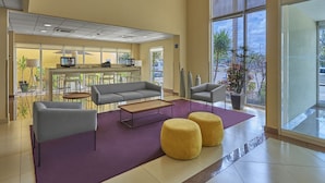 A modern lobby with a sofa, chairs, a coffee table, and a large window offering a view of the street. - City Express by Marriott Campeche (Campeche)
