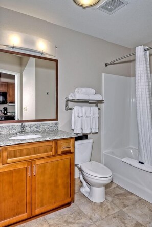 A bathroom with a sink, mirror, toilet, and shower.