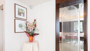 A reception area with a reception desk, framed floral artwork, and a decorative vase with flowers. - Tabist Changtee Hotel (Tokyo)