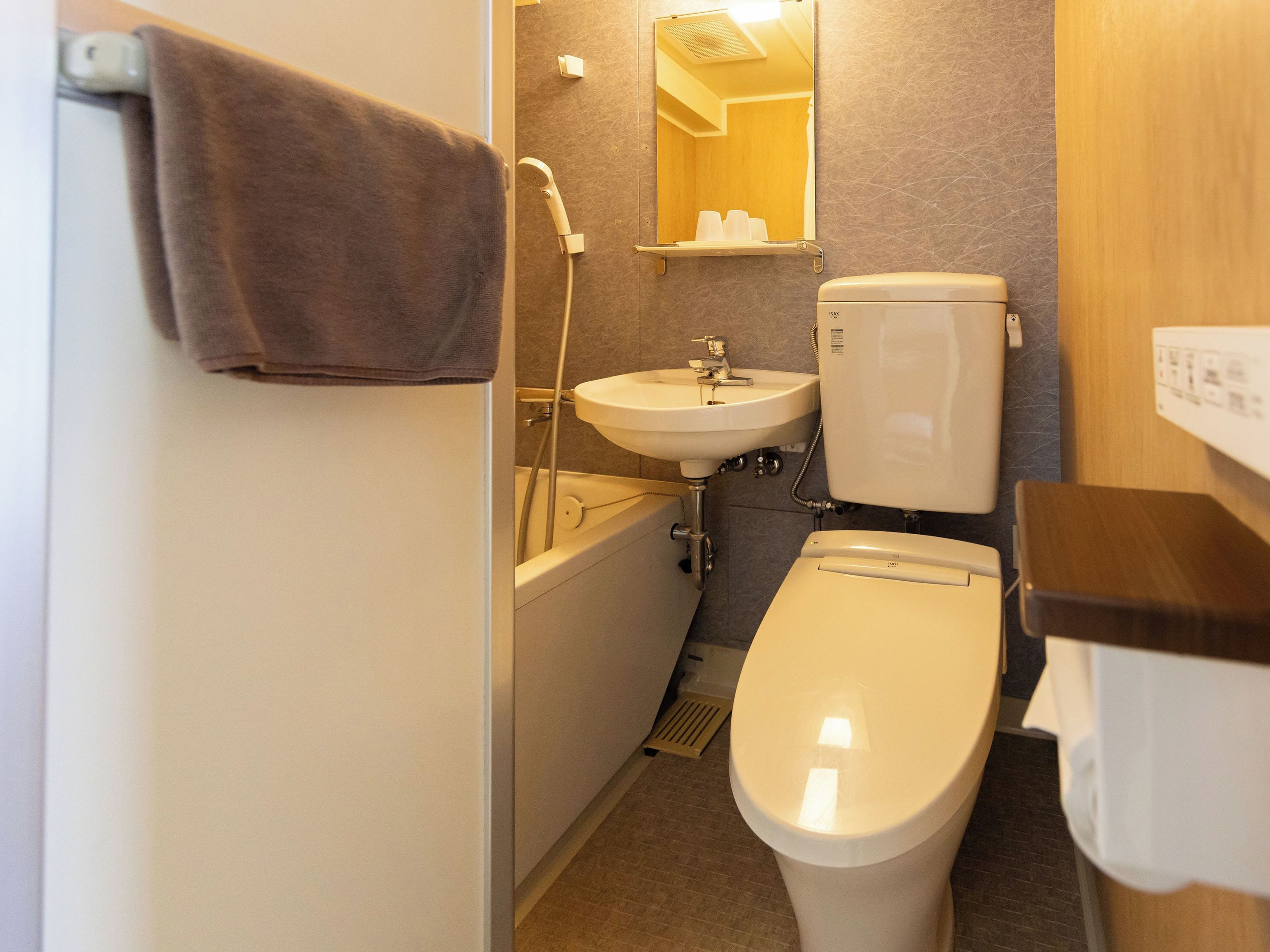 A compact bathroom with a toilet, sink, and shower.