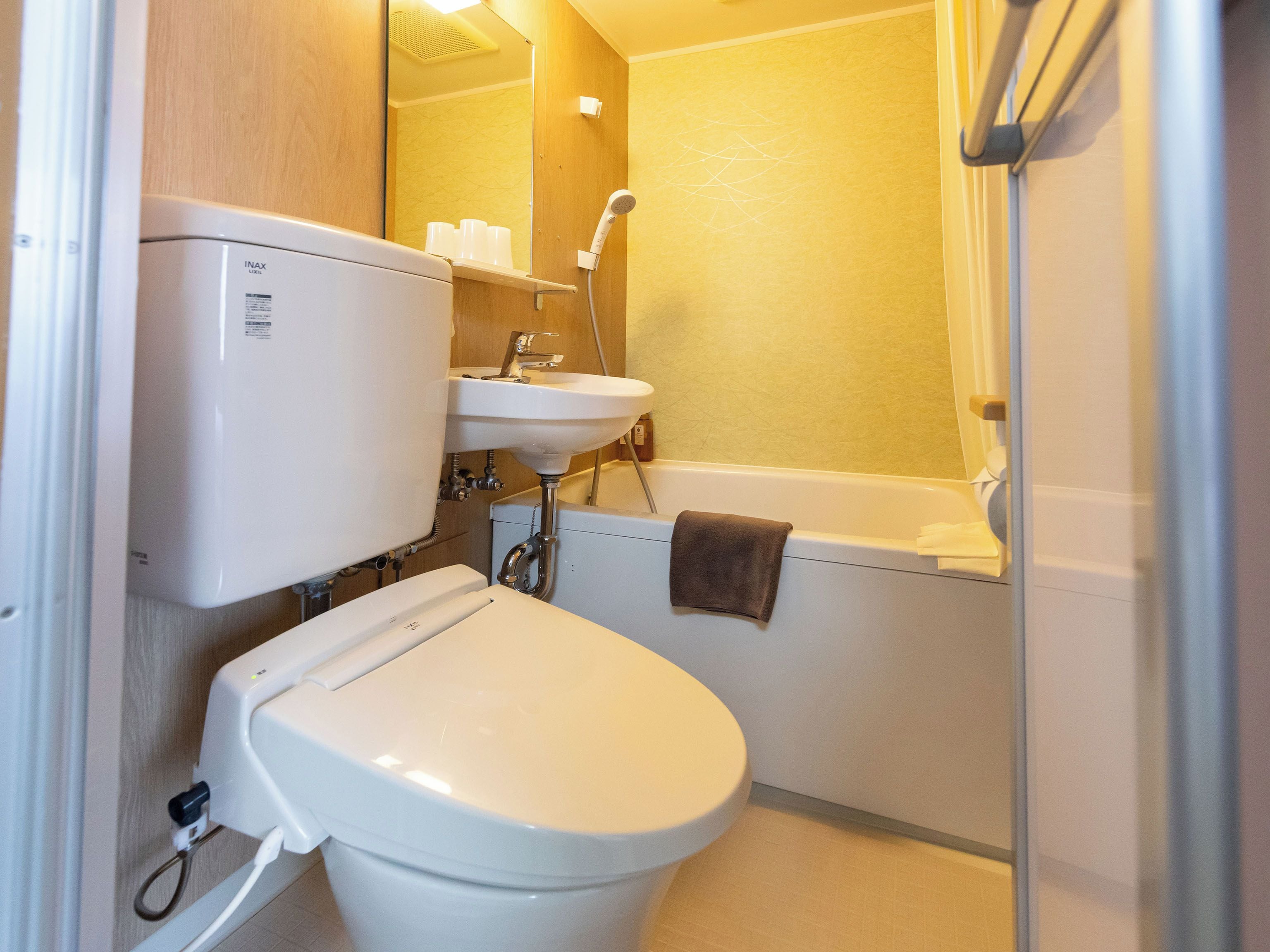 A compact bathroom with a toilet, sink, and shower.