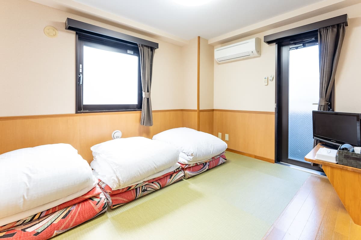 Quarto de hotel com duas camas, televisão, ar condicionado e janela com cortinas.