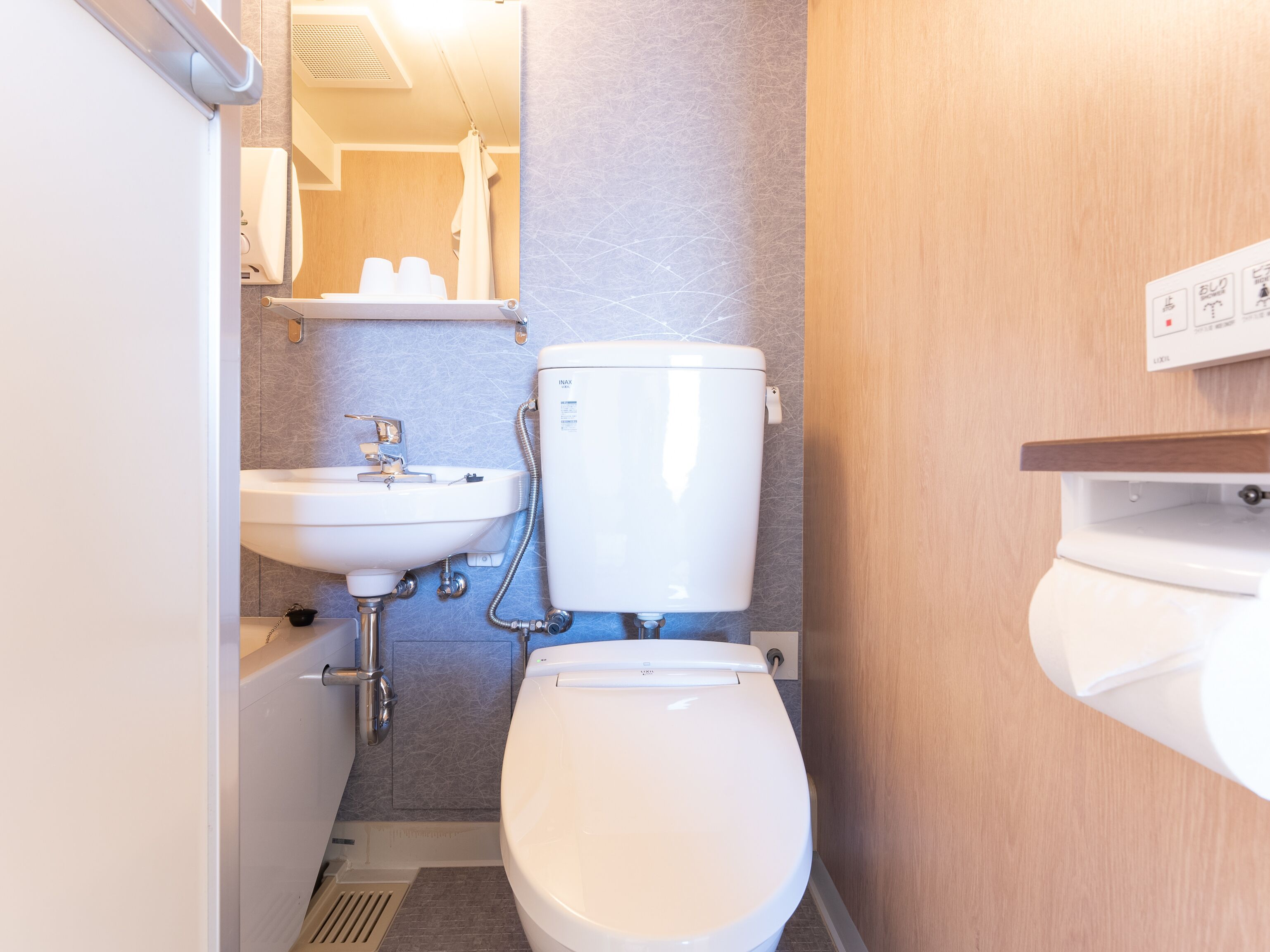 A compact bathroom with a white toilet, a sink, and a shower area.
