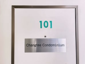 Een bord met het nummer 101 en de tekst 'Changtee Condominium'.