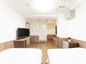 A hotel room with two beds, a TV, a desk, a small fridge, a mirror, and a potted plant. - Tabist Changtee Hotel (Tokyo)