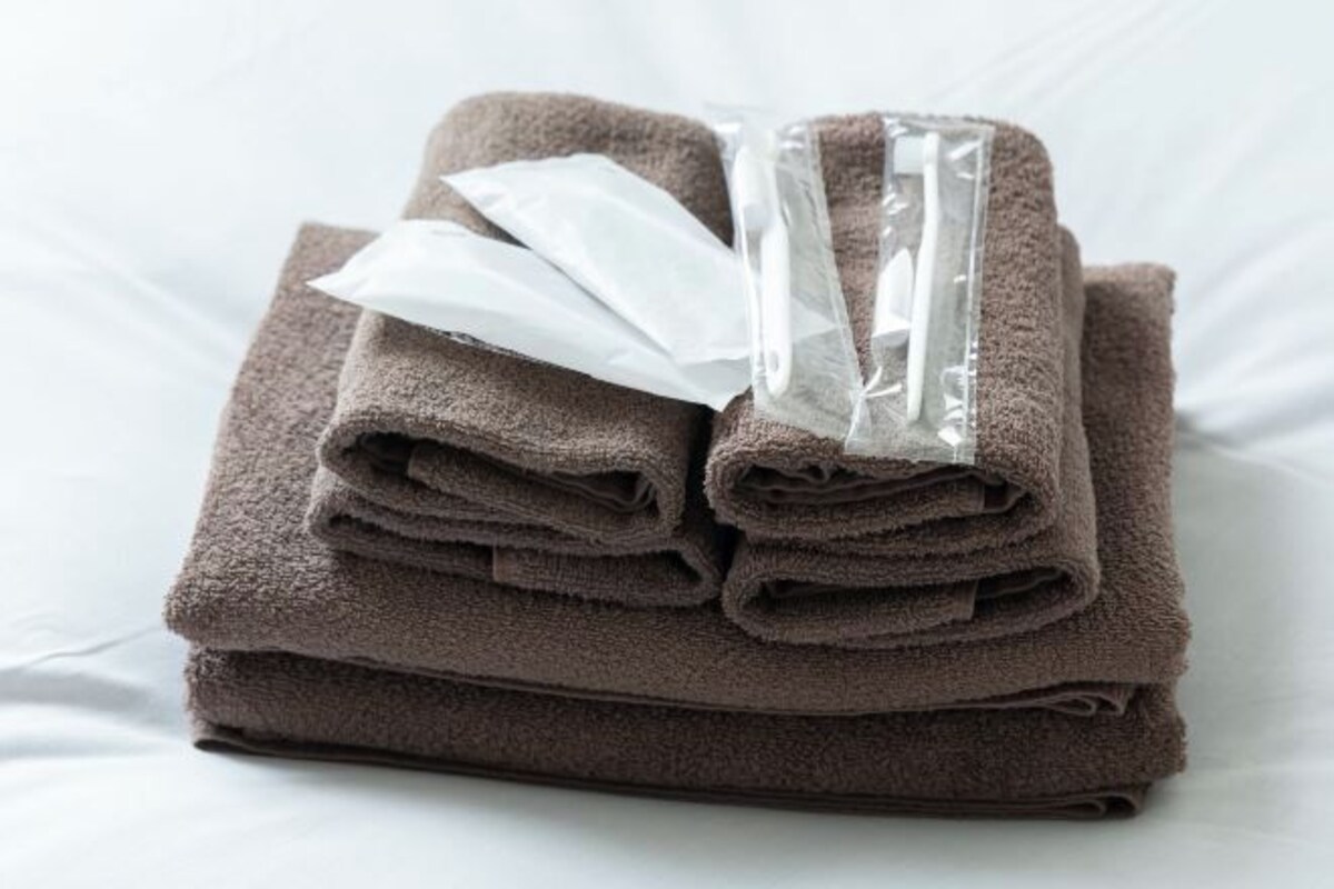 A stack of folded towels with a plastic bag on top, placed on a white surface.