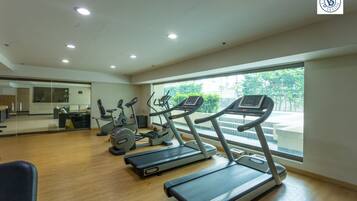 A gym with treadmills, ellipticals, and a mirrored wall.
