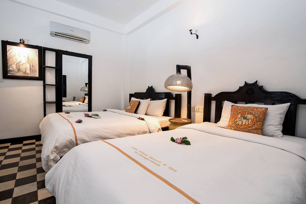 Une chambre d’hôtel avec deux lits, un grand miroir, un appareil de climatisation et une lampe suspendue.