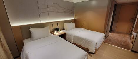 A hotel room with two beds, a nightstand, and a modern headboard.