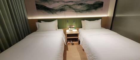Une chambre d’hôtel avec deux lits simples, une table de chevet avec une lampe et un tableau accroché au mur.