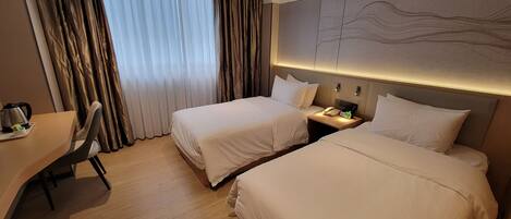 Habitación de hotel con dos camas, un escritorio y un ventanal grande con cortinas.
