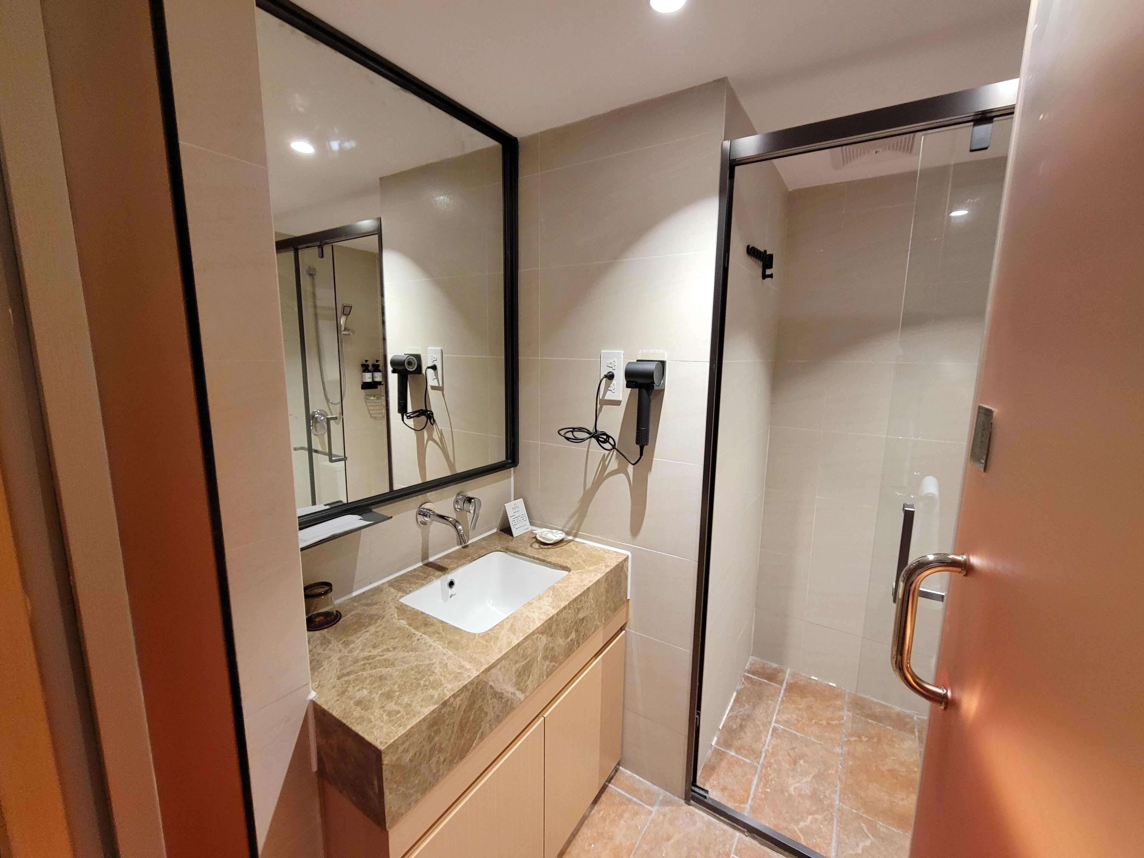 A modern bathroom with a large mirror, a sink, and a shower area.