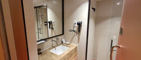 A modern bathroom with a large mirror, a sink, and a shower area.