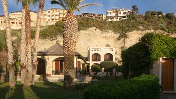 A Mediterranean-style villa with a courtyard, palm trees, and a hillside view.