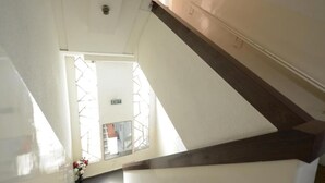 Eine Treppe mit dunkler Holzhandlauf und weißen Wänden, die zu einer Ausgangstür führt.
