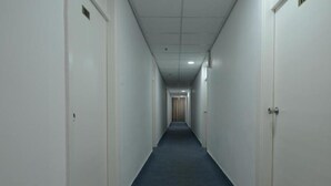 Ein langer, schmaler Gang mit weißen Wänden und Türen an beiden Seiten.