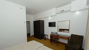 Ein Hotelzimmer mit einem Bett, einem Schreibtisch, einem Sessel, einem Fernseher und einem Kleiderschrank.