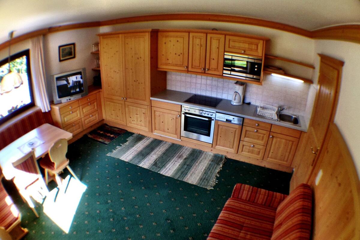 A compact kitchen with wooden cabinets, a microwave, an oven, and a sink.
