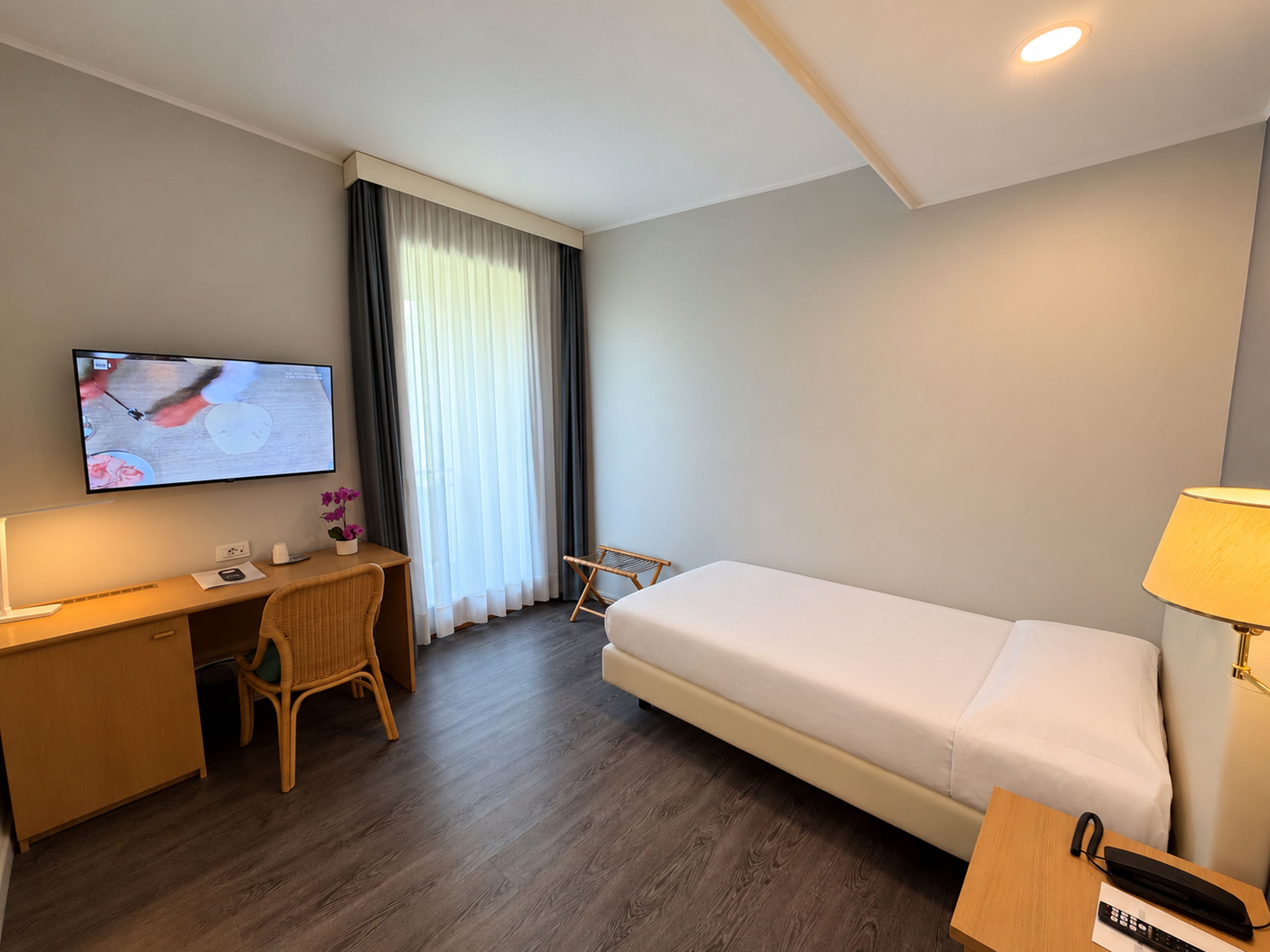 Habitaci ó d'hotel amb llit, escriptori, cadira, televisió i làmpada.