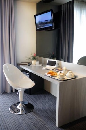 A hotel room with a modern desk, a flat-screen TV, a laptop, a chair, and a tray with breakfast items. - Hotel Ristorante Primavera (Godega di Sant'Urbano)
