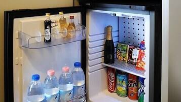 A mini-fridge with a digital lock, containing bottled water, soda, and snacks.