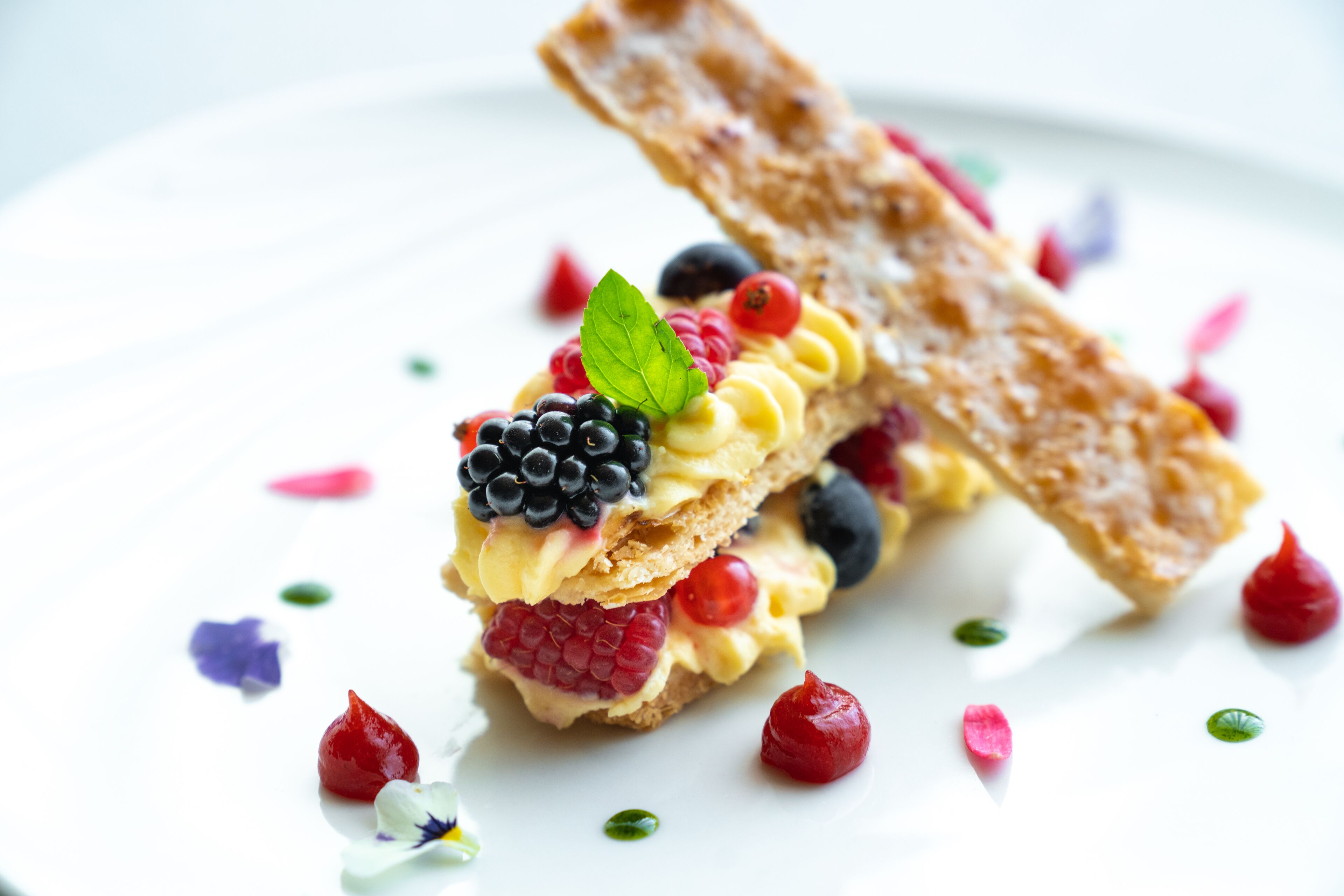Postre amb fruita i una porció de pastís sobre un plat blanc.