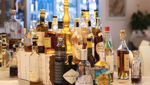 A table with various bottles of alcohol, a lamp, and a bar in the background.