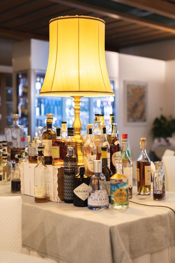 A table with various bottles of alcohol, a lamp, and a bar in the background. - Hotel Ristorante Primavera (Godega di Sant'Urbano)
