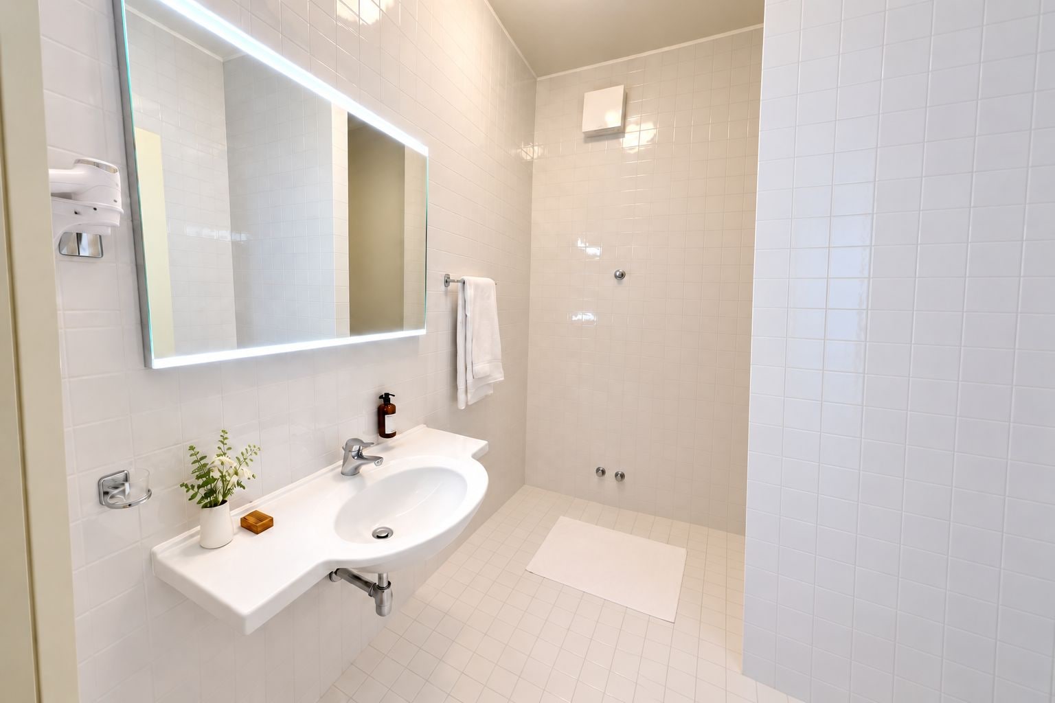 Un bagno moderno con lavandino bianco, specchio e cabina doccia.