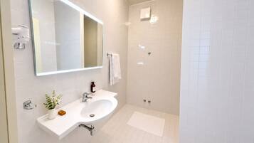 Un bagno moderno con lavandino bianco, specchio e cabina doccia.