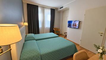 Une chambre d’hôtel avec deux lits, une télévision, un bureau et une chaise.