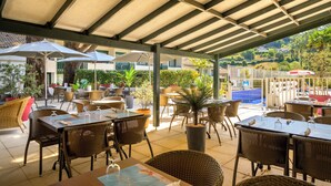 An outdoor patio area with tables and chairs, umbrellas, and potted plants. - Village Club Le Saint Ignace (Ascain)