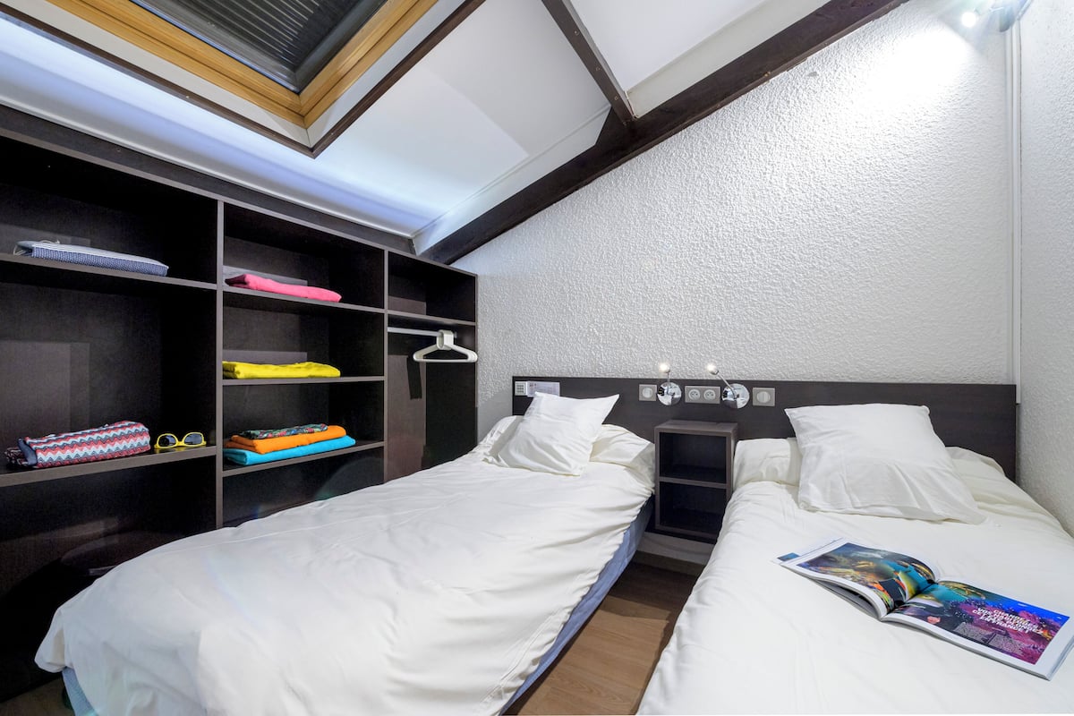 A room with two beds, a wardrobe, and a skylight.